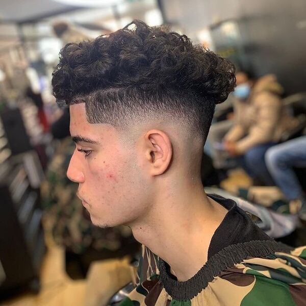 Blowout Curl with Blowout Fade Haircut - a man wearing military design cape.