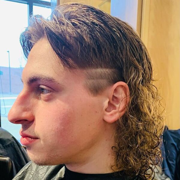Curly Mullet with Layered Side Eboy Haircut - a man wearing barber cape.