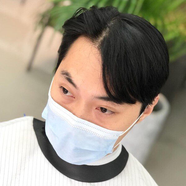 Korea Curtain Hairstyle - a man wearing a barber cape.