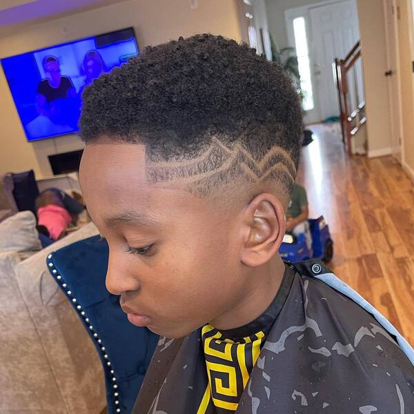Natural Curl Buzz Cut with Lightning Bolt - a boy wearing a black barber cape.