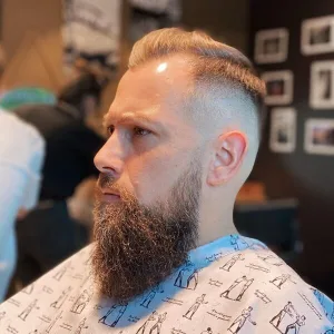 One-sided Comb Balding Crown Hairstyle - a man wearing a printed barber cape.