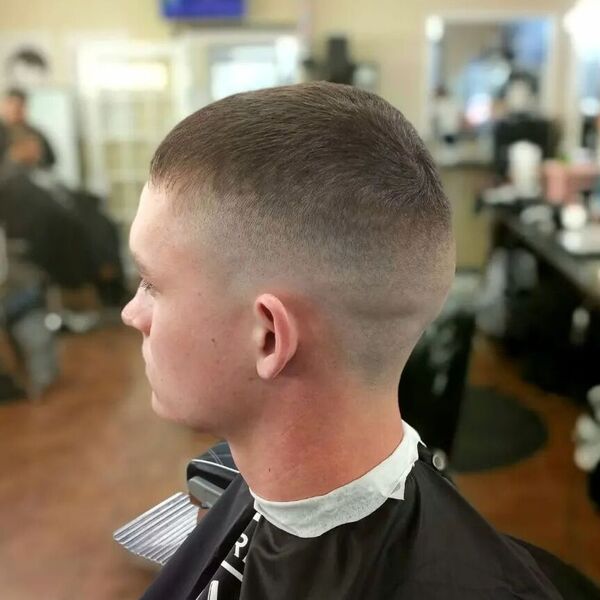 High Skin Fade Navy Cut - a guy in a barber shop wearing a black cape