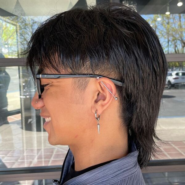 Modern Mexican Mullet - a man wearing glasses with lobe and helix earrings.