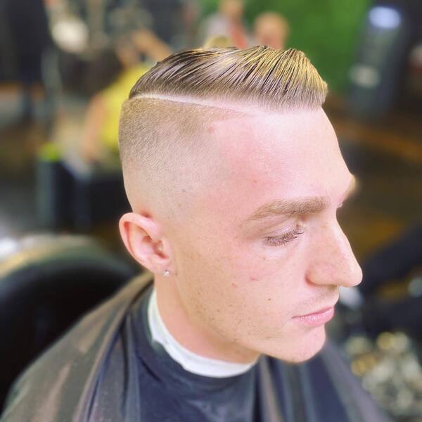 Slick Comb Over with Skin Fade- a man wearing a black barber's cape