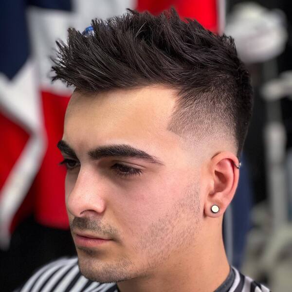 Spiky Comb Over with Taper Fade- a man wearing a black and white stripe barber's cape