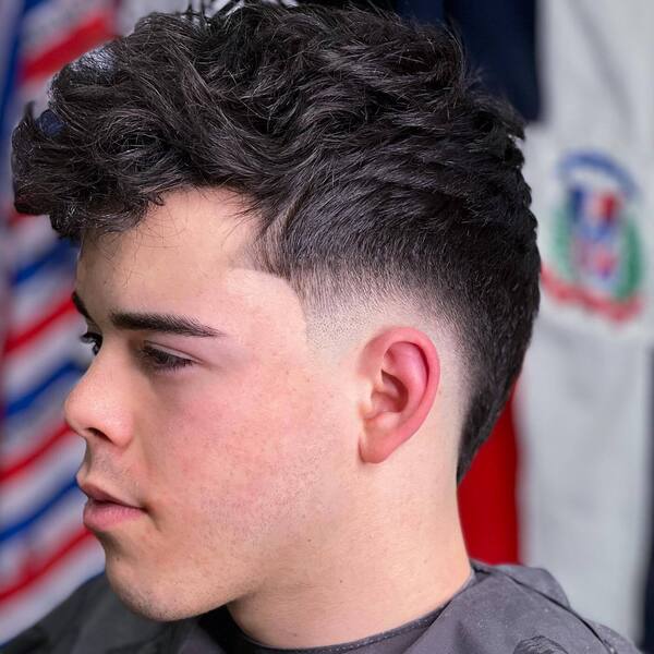 Textured Wavy Reverse Mullet - a man wearing black barber cape.