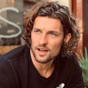 Curly Bob Haircut with Surfer Hairstyle - a man wearing a black shirt