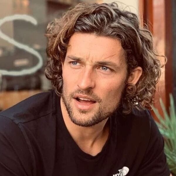 Curly Bob Haircut with Surfer Hairstyle - a man wearing a black shirt