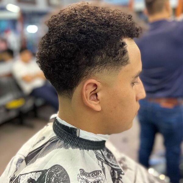 taper fade curly hair - wearing a white cover with different designs