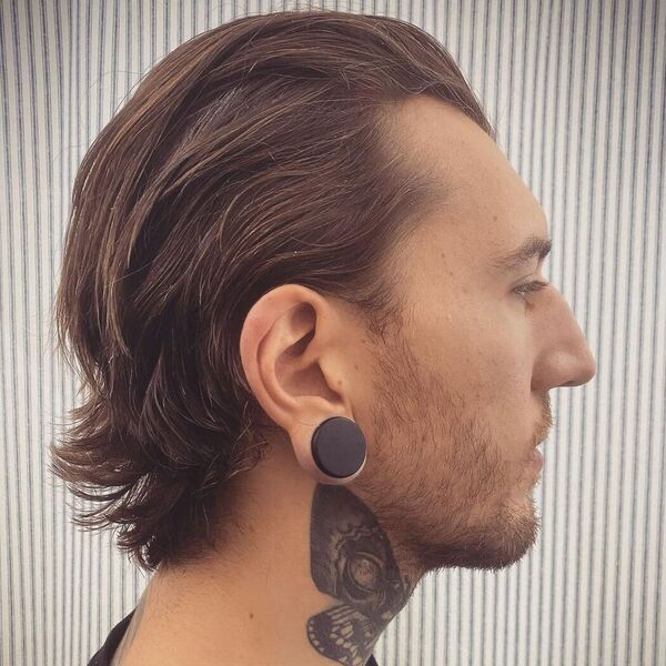 wearing a big black earring and has a tattoo on his neck