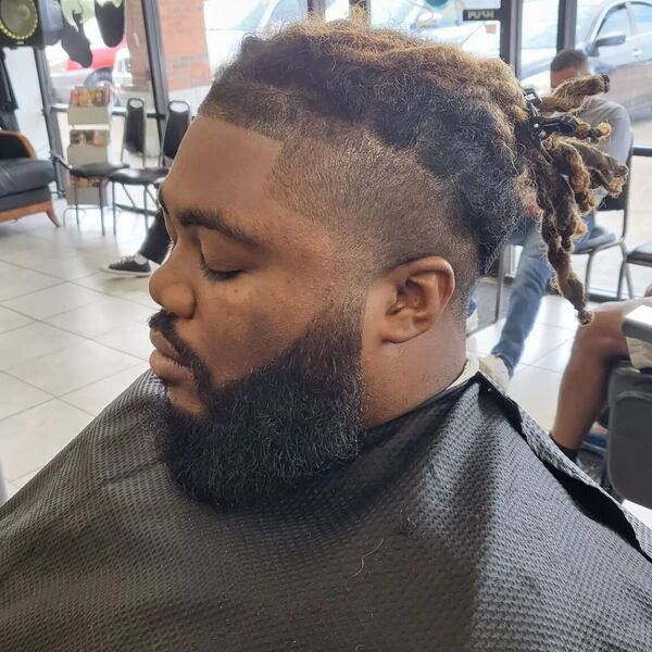 Low Taper Fade - wearing a black cover and has a thick hair bread
