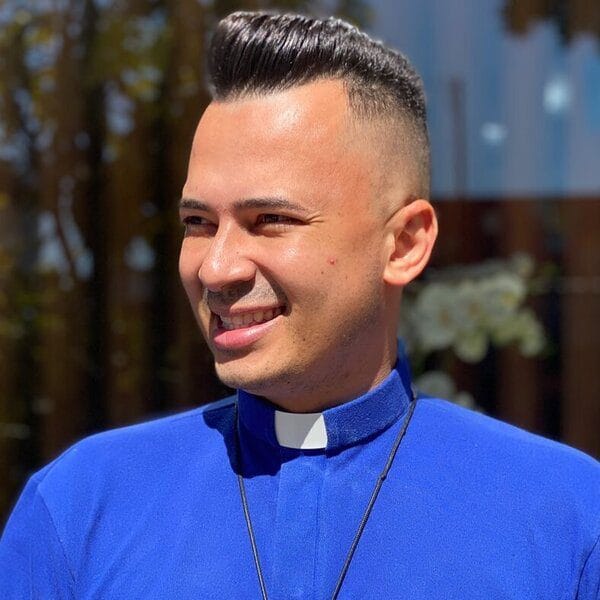 wearing blue polo with long black necklace