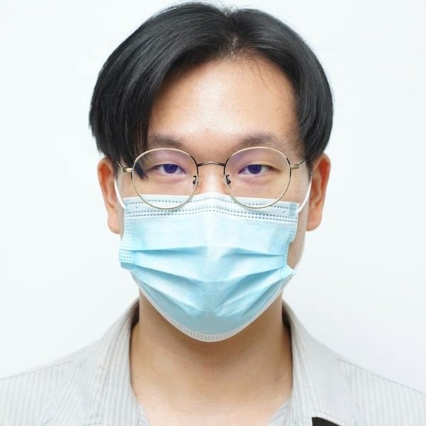 A man wearing a formal polo and gold eyeglass and a facemask