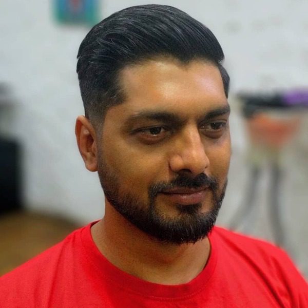 A man wearing plain red shirt with his Indian hair