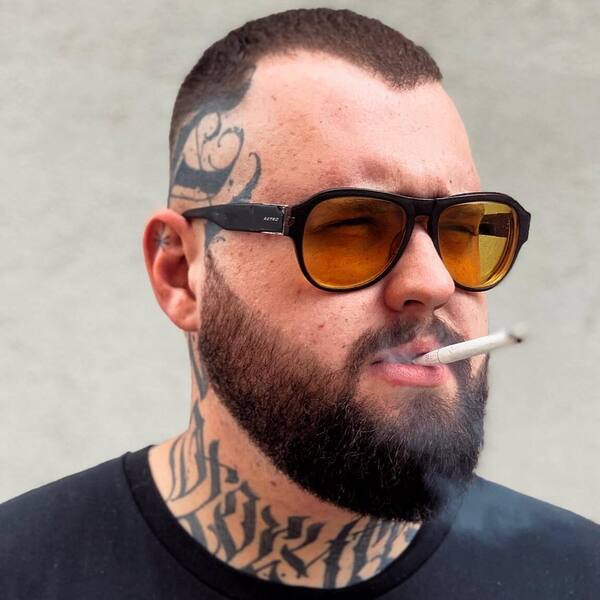 A man wearing sunglass with full of tattoo