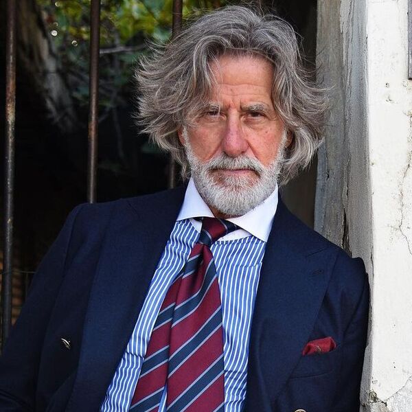 A man wearing a formal tuxedo attire with stripped necktie with his one of the famous hairstyles for men in 50s